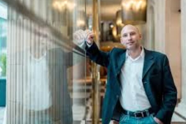 Pascal Bachmann, international speaker and business strategist, standing confidently in a modern hallway with glass reflections.